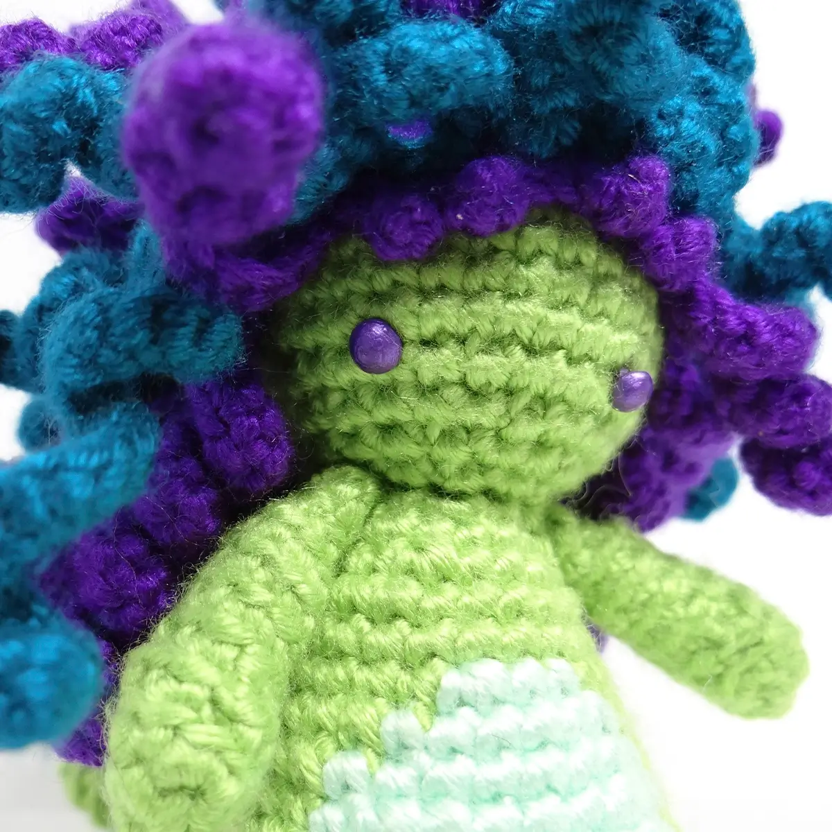 Detalle de ojos y cabello de Medusa amigurumi morado y turquesa